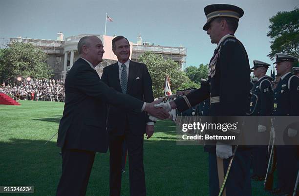 Washington: As President Bush looks on, Soviet leader Mikhail Gorbachev shakes hands with Col. Barrie E. Zais, commander of the 3rd U.S. Infantry...