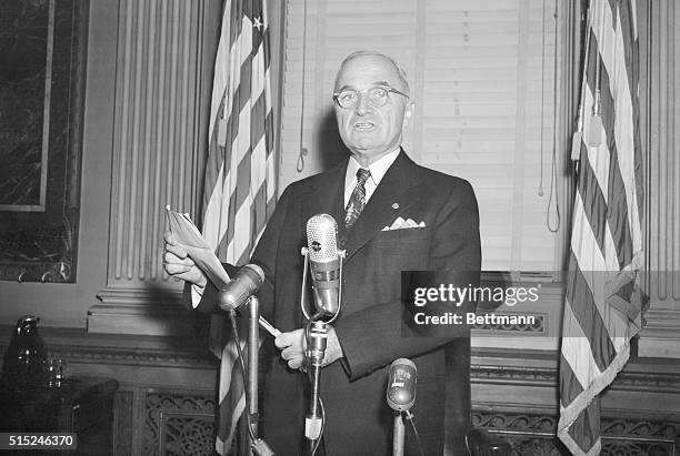 Following his press conference today , President Harry S. Truman poses for photographers reading the statement in which he grimly warned Communist...