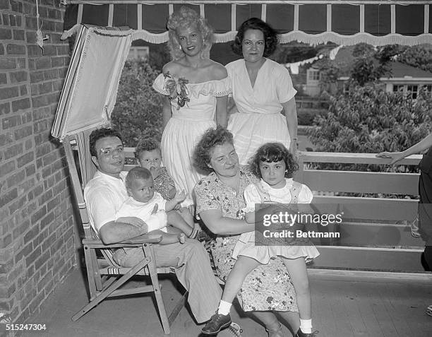 Jake Lamotta is seated with his family around him. His wife Vicki is wearing a white dress off her shoulders.