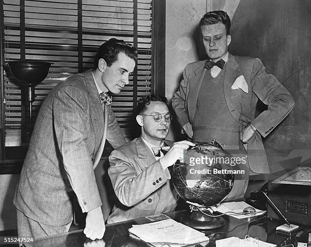 The Rev. Charles B. Templeton , Dr. Torrey Johnson and the Rev. Billy Graham are shown outlining their projected European tour on a globe yesterday...