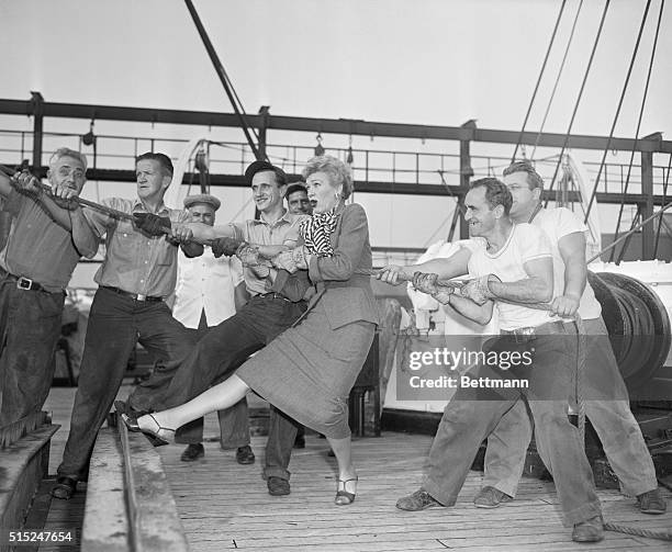 American radio and television actress Eve Arden helps longshoremen aboard the Ile de France as they pull into port.