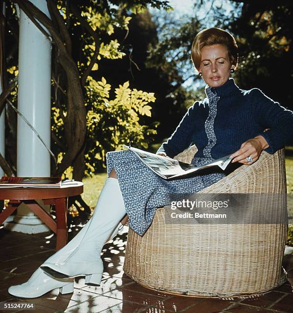 Sonia McMahon, wife of the Australian Prime Minister William McMahon, seated on a patio, reading a magazine.