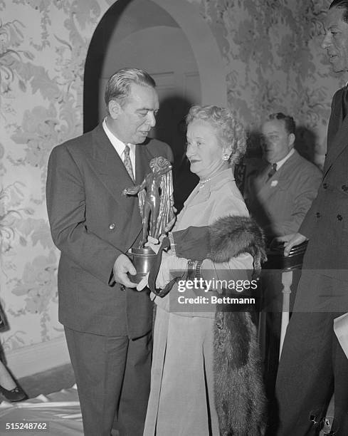 This photo shows Mayor of NYC O'Dwyer as he presents the American Fashion Critics Award to Hattie Carnegie at Gracie Mansion.