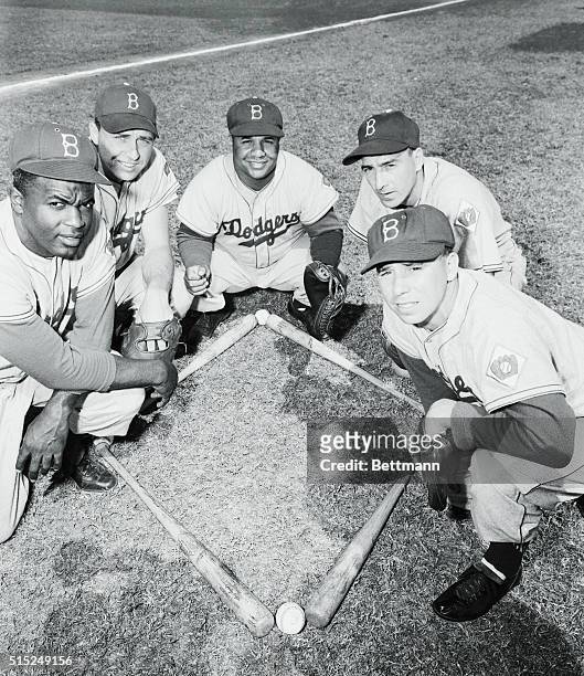 Photo shows the Brooklyn infield players as they group around bat and ball diamond. They are Jackie Robinson, Gil Hodges, Roy Campanella, Billy Cox,...