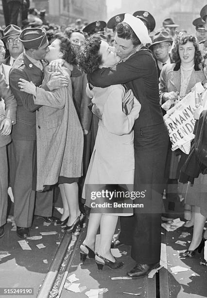 While watched by a celebrating crowd, women get kissed by US military men at Times Square on V-E Day, May 7, 1945.