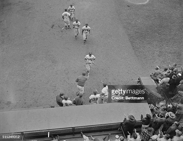 Gil Hodges of the Brooklyn Dodgers, is being greeted at the dugout by his teammates, after hitting an eighth inning home run in the game against the...