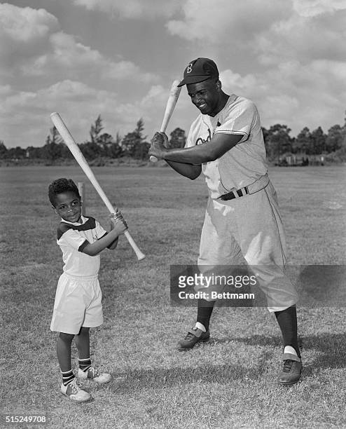 Jackie Robinson, , the baseball star, is shown here teaching his son Jackie Jr. How to bat.