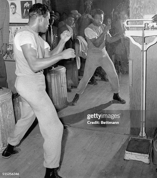 Confidant of a comeback, Sugar Ray Robinson works out before a mirror in a Detroit gymnasium on the eve of his bout with Joe Rindone of Boston. The...