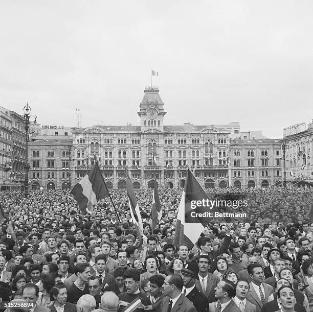 Cheering citizens of Trieste wave flags in the Piazza Municipale after the partitioning accords between Italy and Yugoslavia were signed in London,...