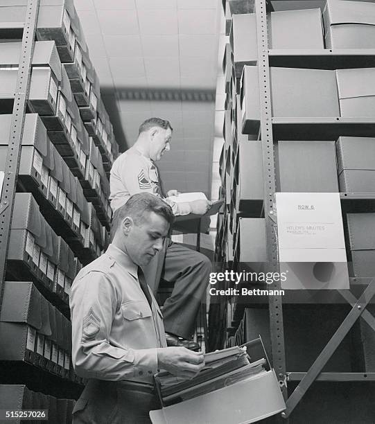 Captured Nazi documents which fill stacks of file cabinets at the former naval torpedo factory near Washington are inspected by M/Sgt. Ignaz Ernst...