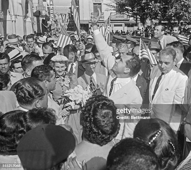 Vice President Richard Nixon waves a greeting to window watchers overhead after his arrival in San Juan, February 27th. At left, holding bouquet, is...