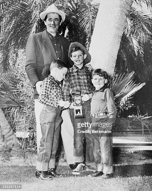 The cowboy flavor is strong as Gregory Peck and his three sons gather for a family photo after a visit to the rodeo at Palm Springs. Daddy is clean...