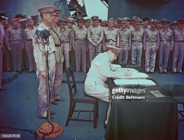 General of the Army, Douglas MacArthur, Supreme Commander for the Allied Powers, signs the Japanese surrender document aboard the battleship, U.S.S....