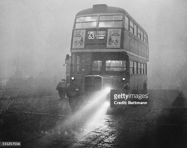 London double-decker bus, seemingly riding in space, makes its way along a fog-blanketed embankment with "fog lamps" to help it along as the city...