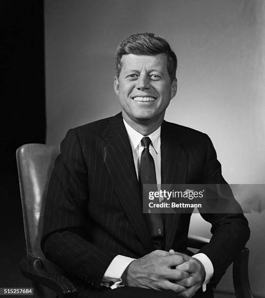 John Fitzgerald Kennedy. Adjusting tie and looking towards floor. Photograph dated 1/28/60.