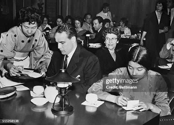 Showing that he still likes France Nuyen, the exotic French-Chinese lovely. Here actor Marlon Brando pays his check as he and France make a hurried...