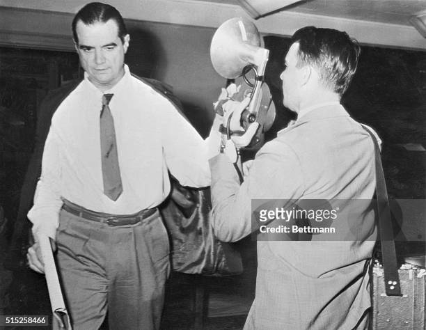 As he departed from the courtroom where Howard Hughes' left hand is apparently doing TV cameraman Harry Watson's camera no good. Hughes denies that...