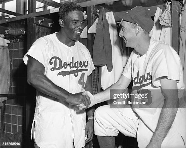 Jackie Robinson and Billy Cox, of the Brooklyn Dodgers, are shown shaking hands in the Dodger Clubhouse at Vero Beach to counter-act the rumors that...