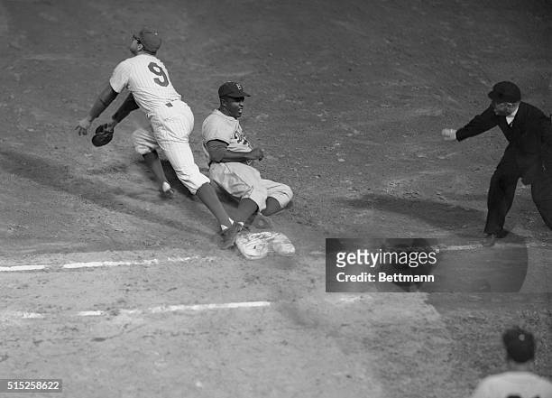 Earl Torgenson, Phillies first baseman looks up in the air for the ball as Jackie Robinson, Brooklyn's left fielder, slides back safe at first when...