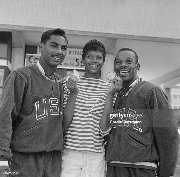 America's Wilma Rudolph, winner of Gold Medals in the 100 meter and 200 meter dashes, displays the Gold Medals won by US boxers Wilbert MCClure and...