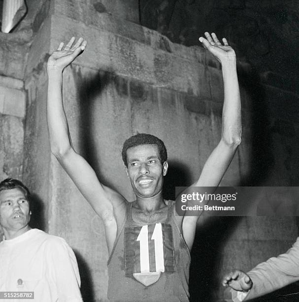 Ethiopian runner Abebe Bikila waves to the cheering crowd and photographers after he won the Olympic Marathon in a time of about 2 hours, 15 minutes...