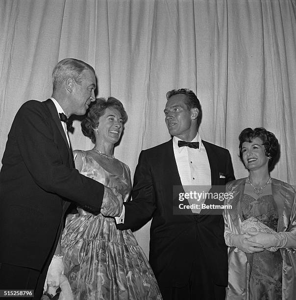 Hollywood, Los Angeles, California: Actor James Stewart, with his wife, leans over to shake hands and say hello to Charlton Heston and his wife as...