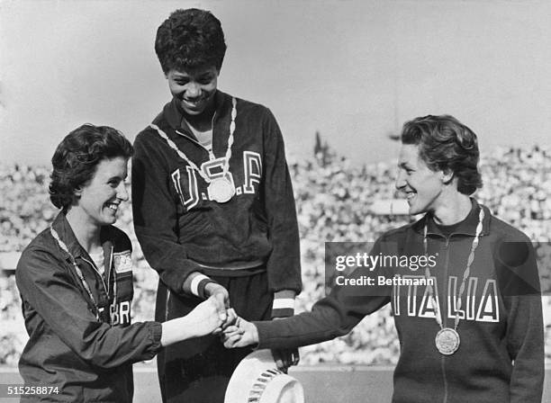 America's Wilma wears her gold medal as she stands on the podium in the awards ceremony after winning the women's dash here, Slept. 2nd. At left is...