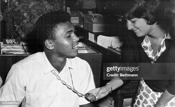 Italian miss pauses to admire the gold medal Worn by Cassius Clay after winning the Olympic Light Heavyweight Crown.