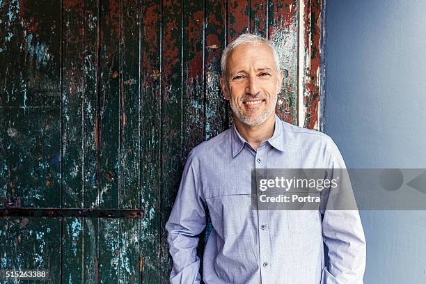 confident businessman standing against wooden wall - 40's rumpled business man stockfoto's en -beelden