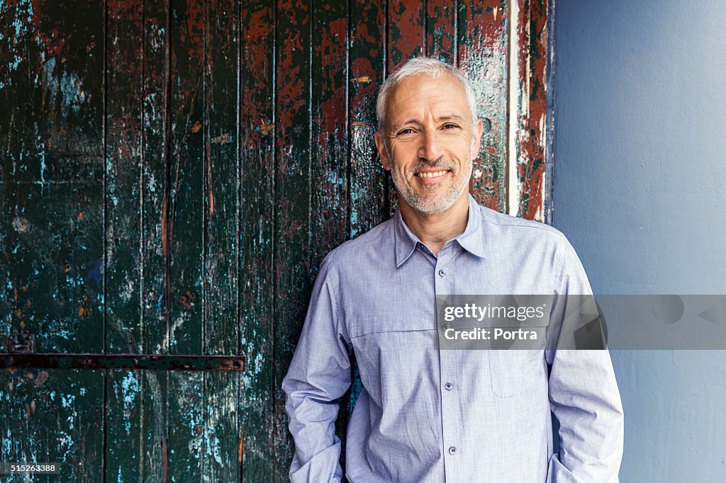 Confident businessman standing against wooden wall