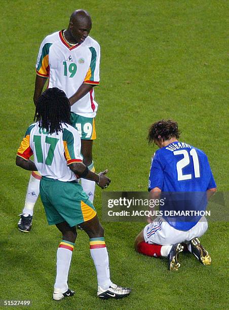 France's Christophe Dugarry sits dejected as Senegal's Pape Bouba Diop and Ferdinand Coly look on at the end of their match in 2002 FIFA World Cup...