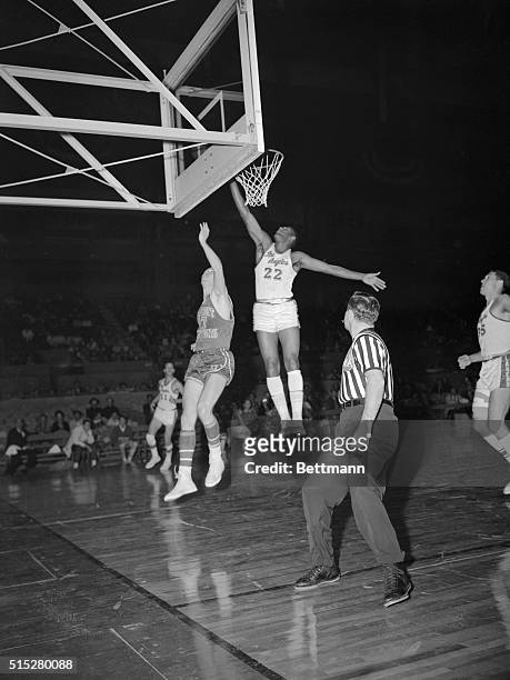 Elgin Baylor , of the Los Angeles Lakers, jumps high for a layup and two points as Detroit Pistons' Jackie Moreland makes a vain attempt to block the...