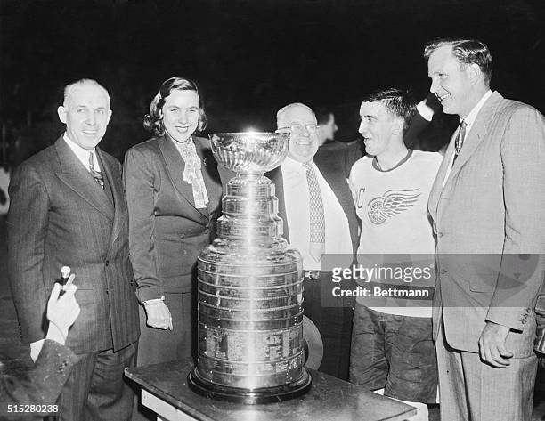 Standing around the Stanley Cup after Detroit's win are, left to right: N.H.L. President Clarence Campbell; Marguerite Norris, part owner of the Red...