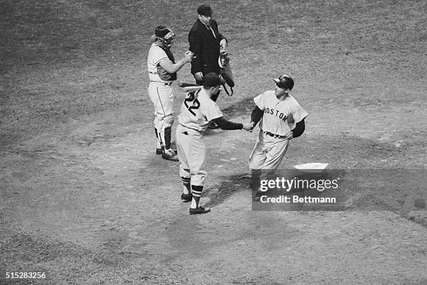 Jackie Jensen gets a handshake from Boston Red Sox teammate, catcher Russ Nixon as he crosses the plate after his seventh inning homer here May 8th....