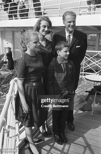 Evangelist Billy Graham and his children relax onboard the liner SS France here April 18, before sailing to Europe. With him are his daughters Bunny...