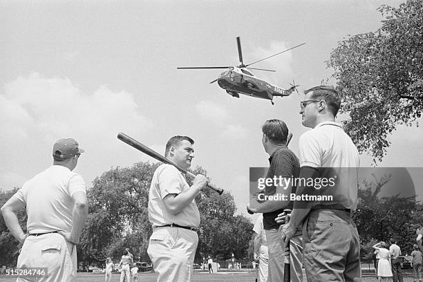 Members of the White House staff pause during a baseball game against members of the Senate Foreign Relations staff while Marine One flies overhead....