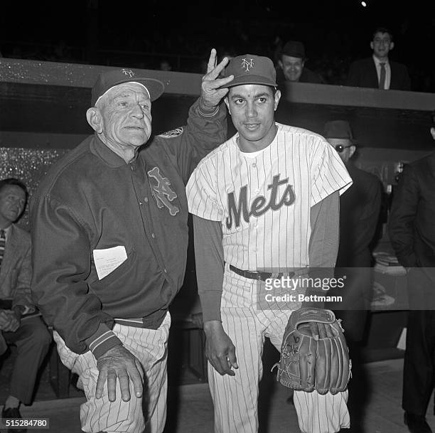 New York Mets' manager Casey Stengel tries on hat on new Mets' man Chico Fernandez after he donned Mets uniform for first time prior to game with...