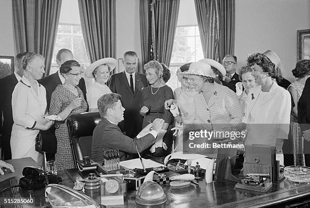 President Kennedy hands out pens during a ceremony at the White House today in which he signed into law a bill aimed at assuring women of paychecks...