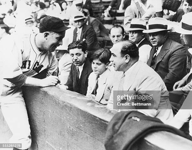 Al Capone with his party at the charity game between the White Sox and Cubs in Chicago in 1931. Gabby Hartnett of the Cubs is shown autographing a...