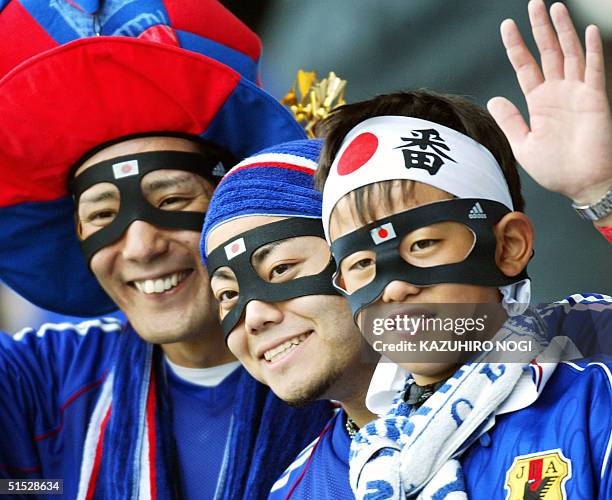 Japanese soccer fans wear protective masks like Japan's defender Naoki Matsuda as they cheer at Miyagi Stadium, Japan, 18 June, 2002 before match 55,...