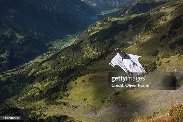 wingsuit base jumper is flying down a mountain - wingsuit stock-fotos und bilder