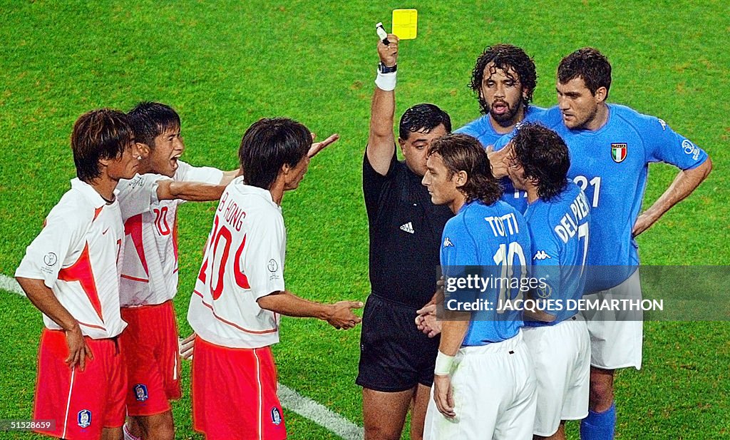 Referee Byron Moreno of Ecuador (C) hands out a ye