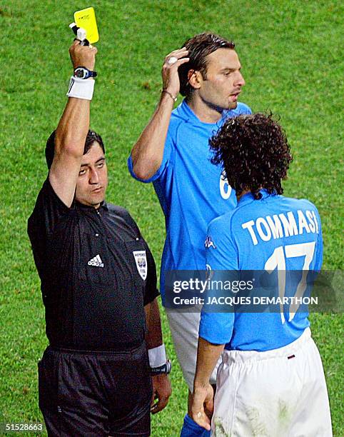 Referee Byron Moreno hands out a yellow card to Italian midfielder Damiano Tommasi as teammate Cristiano Zanetti reacts during their second round...