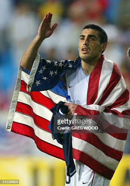 Captain Claudio Reyna drapes himself in an American flag as he walks off the pitch, 21 June 2002 at the Munsu Football Stadium in Ulsan, during...