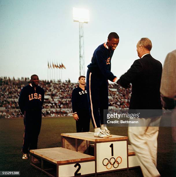 Bob Beamon stands with white socks exposed on victory podium after winning the gold medal in the Men's Long Jump event, Oct. 18th, with a record leap...