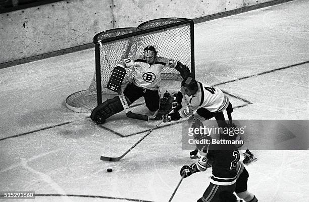Bobby Orr of the Bruins lends a hand to goalie Gerry Cheevers as he skates puck out as Brad Park of the Rangers tries to get Orr and pucks during...
