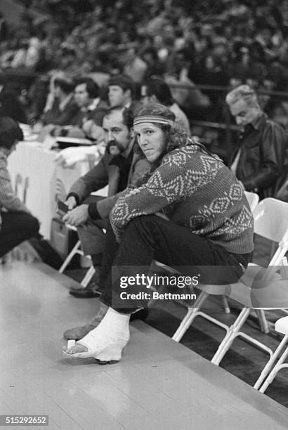 Trail Blazers' rookie center Bill Walton sits on bench ¾ and watches his teammates defeat Cleveland Cavaliers, 117-98. Team physician has placed...