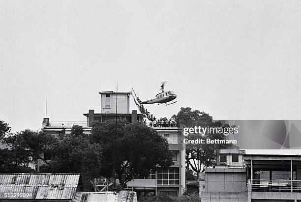 Employee helps Vietnamese evacuees onto an Air America helicopter from the top of 22 Gia Long Street, a half mile from the U.S. Embassy.