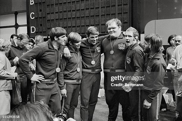 Munich, West Germany: Olympic medals dangling from around their necks, arms around each others' shoulders, are United States wrestlers at awards...