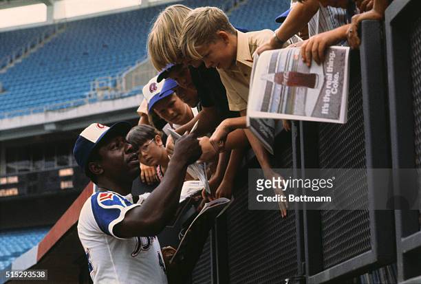 Hank Aaron of the Atlanta Braves signs autographs for admiring youngsters here recently. Aaron helped the Braves subdue the Mets 3-1, at Shea Stadium...